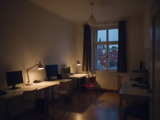 The studio in the evening, lamps on, Prague at dusk outside.